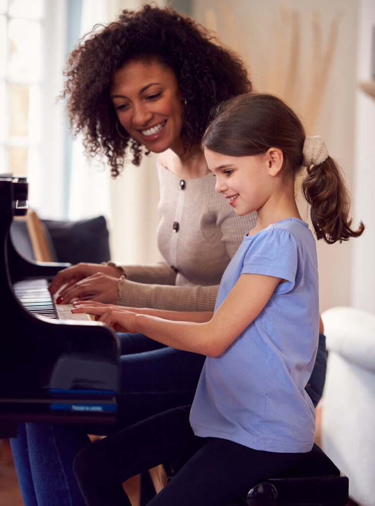 Kind lernt mit einer Erwachsenen Klavier spielen