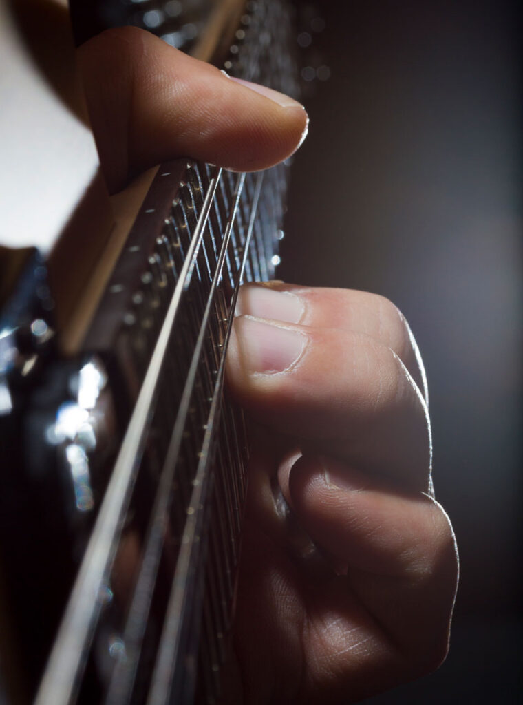 Hand greift Akkorde auf einer Gitarre