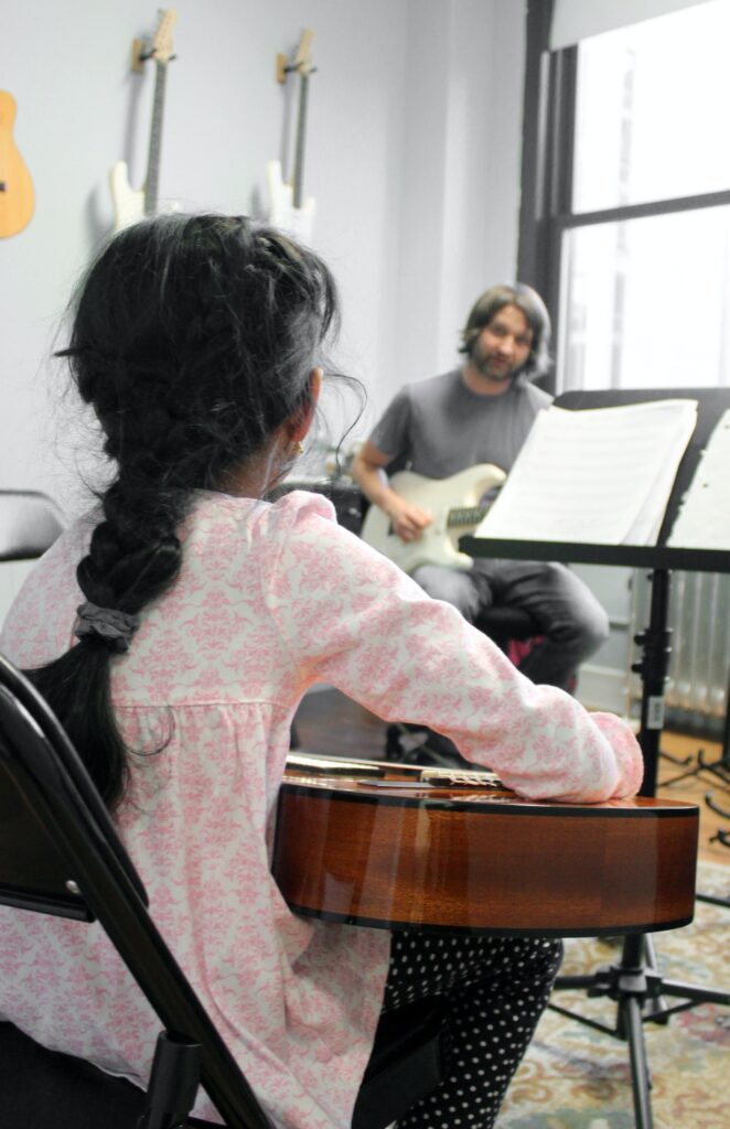 Kind mit Gitarre beim Musikunterricht